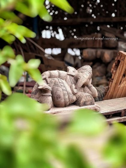 Another artistic shot of the reclining Ganesha, viewed through foliage, emphasizing its tranquil and natural essence.
