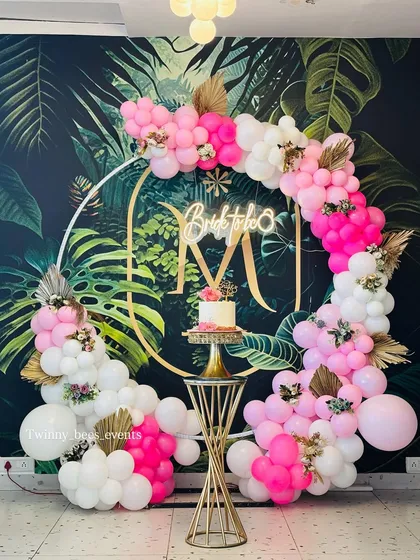 This vibrant bachelorette decor features a stunning balloon arch in shades of pink and white against a tropical leaf wallpaper. We added a custom monogram and a neon "Bride to be" sign for a personalized touch.