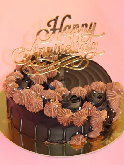 An elegant chocolate anniversary cake. The rich dark chocolate is complemented by delicate piping and a golden "Happy Anniversary" topper.