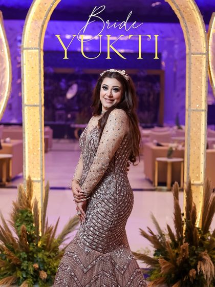 A beautiful solo portrait of the bride on her engagement night. She stands framed by a modern, illuminated archway, her sparkling dress and happy smile setting the tone for the celebration.