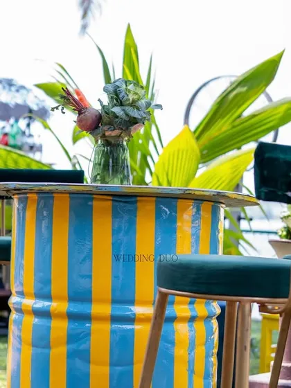 A pop of color for a summer Mehendi. We repurposed a barrel, painting it with vibrant blue and yellow stripes, and paired it with chic teal velvet bar stools for a playful and modern look.