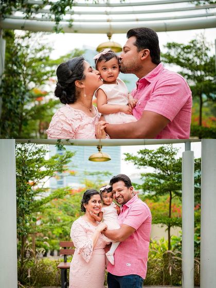 A loving family of three in matching pink outfits, sharing kisses and smiles during an outdoor portrait session.