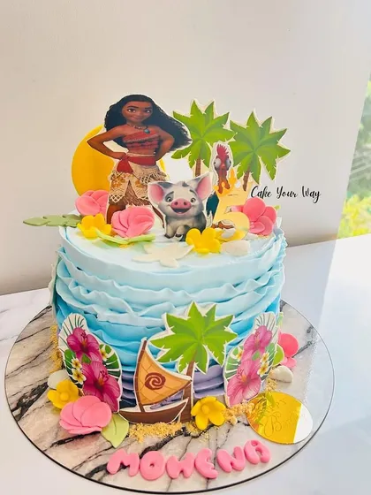 A tropical Moana-themed cake with ocean waves, palm trees, and the adventurous princess herself.