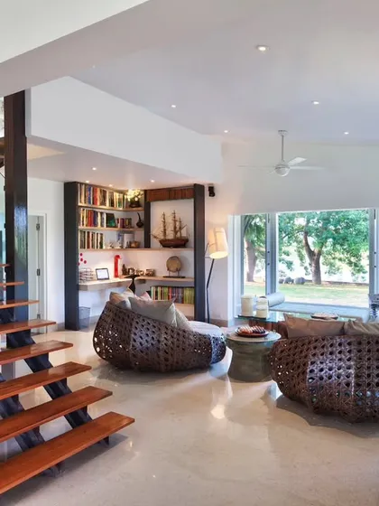 A wider view of the Aishbagh living area, showing the open-plan layout and the large bay window that frames the view of the lake. The design emphasizes natural light and a visual connection to the outdoors.