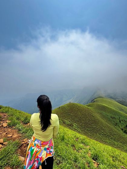 A trekker gazes out at the rolling green hills and misty valleys of Netravati. The view from the top is truly mesmerizing.