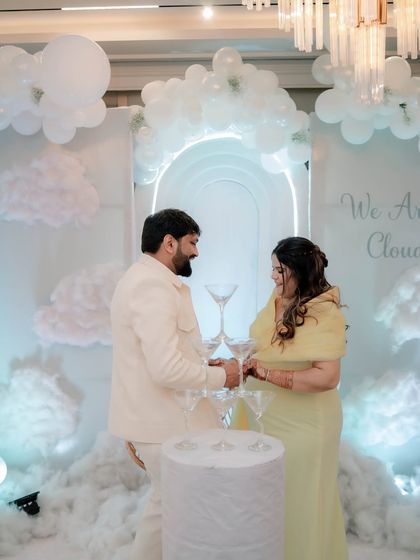 The couple prepares for a champagne toast in front of their 'Cloud 9' backdrop. This is a classic and elegant way to celebrate the new chapter ahead.
