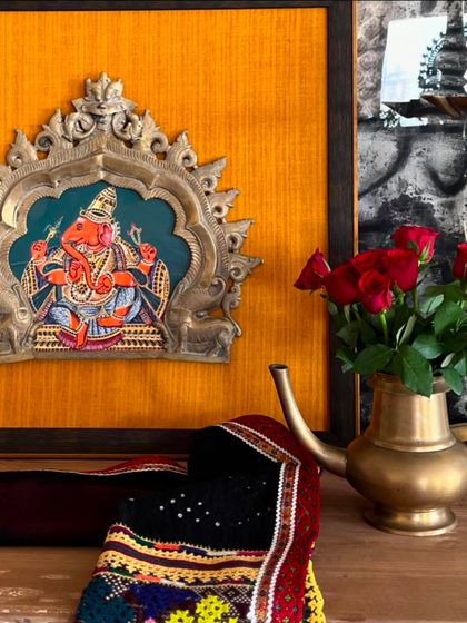 A detail shot of the Ganesha Prabhavali, showing the rich texture of the yellow fabric and the intricate details of the vintage brass halo. It's a perfect blend of old and new.