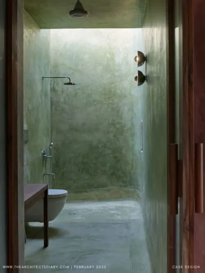 The bathroom at Villa Uma features green-hued plaster walls and a skylight that bathes the space in soft, natural light. The design turns a functional room into a serene, spa-like experience.