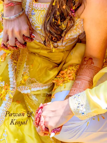 A close-up on the hands, stained with henna and turmeric, holding each other. This detail shot tells a story of tradition, love, and the joining of two lives.