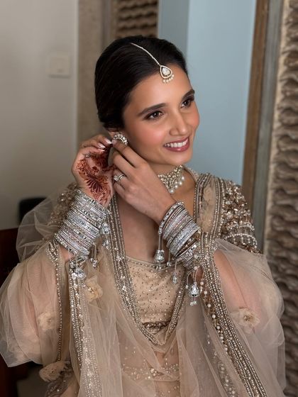 A candid moment of the bride putting on her earrings. Her smile and glowing skin are the best accessories for this soft and dreamy bridal style.