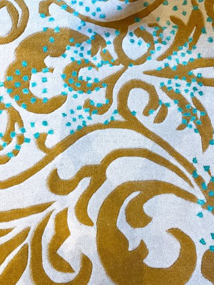 This detail shot highlights the unique texture of our Loops by Zeba collection. Golden swirls are accented with tiny, raised dots of teal, adding a playful and sophisticated touch to the plush ivory background.