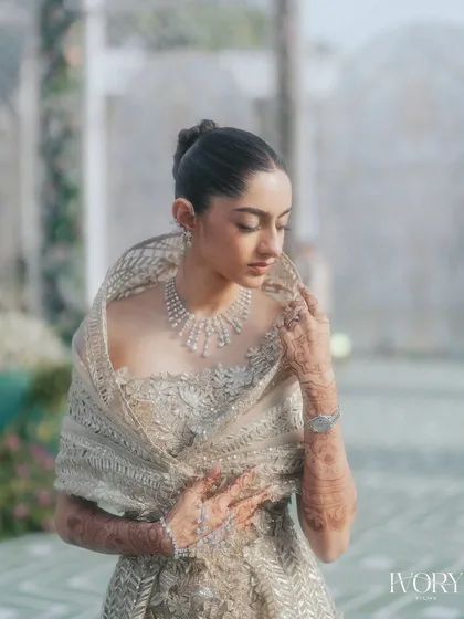 A delicate and graceful bridal portrait. We focus on the intricate details of her jewelry and the soft expression on her face, creating a timeless and beautiful image.