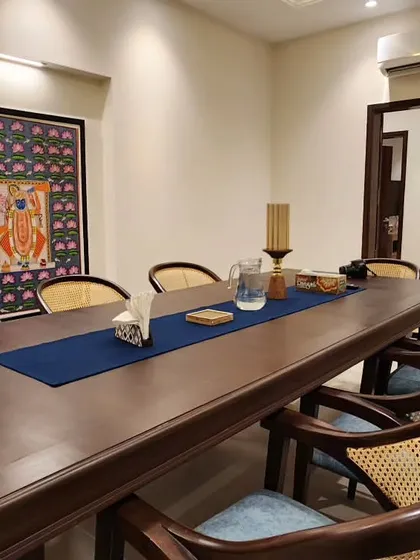 This dining room embodies our philosophy of minimal yet exquisite design. The space is anchored by a traditional Pichwai artwork, its vibrant colors contrasting beautifully with the elegant, textured wallpaper and our custom-designed dark wood dining set.