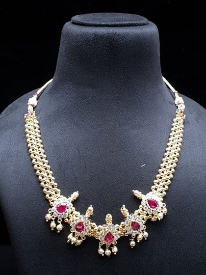A beautiful short necklace with ruby-colored stones and pearl drops. The intricate design makes it look very rich and is perfect for weddings and functions.