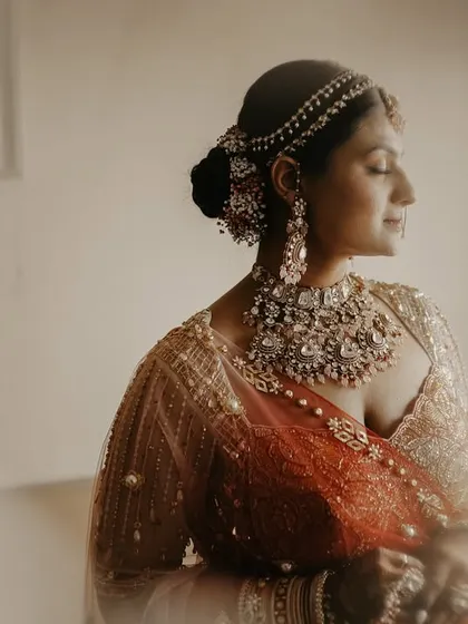 A portrait of quiet elegance. The bride is bathed in soft light, her eyes closed, creating a serene and almost spiritual moment before the wedding ceremony.