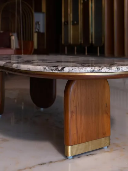 This classic coffee table, with its unique marble top and sculptural wooden base, was custom-designed to complete the living room decor. It perfectly balances form and function.