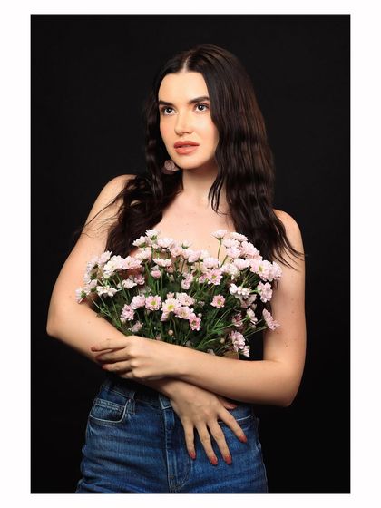A classic portrait of the model holding flowers, looking directly at the camera with a soft expression.