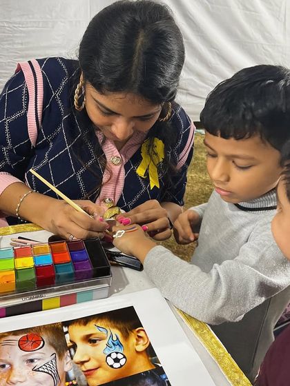 Here I am, painting a design on a young boy's hand at a school carnival. I use skin safe paints and can create a wide variety of fun designs for children.