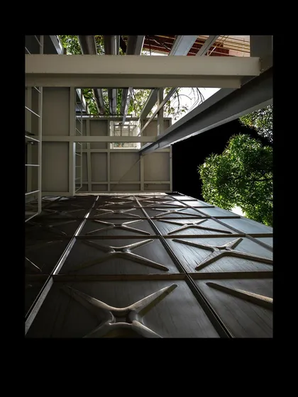 An upward view of the MAP facade at night, highlighting the texture of the pressed steel panels. This detail, inspired by common water tanks, connects the monumental building to an everyday object, grounding it in a local context.