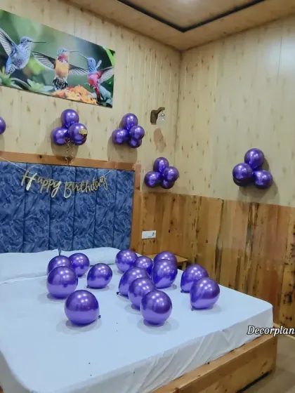 Another angle of the simple purple balloon decoration, showing how it can brighten up a room with wood-paneled walls. The metallic shine of the balloons adds a touch of elegance.
