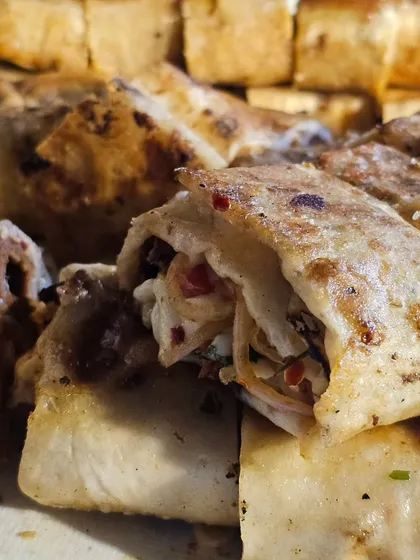 A close-up of our stuffed and grilled flatbread, a unique and savory starter that combines soft bread with a flavorful filling.