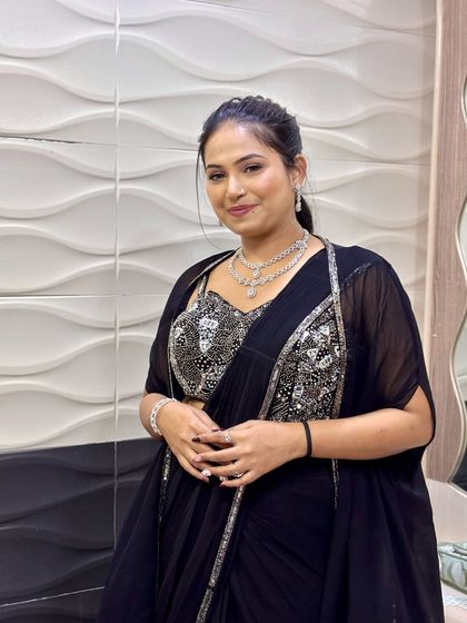 A client ready for a party in a modern black saree. Her hair is styled in a sleek ponytail, a chic and contemporary choice.