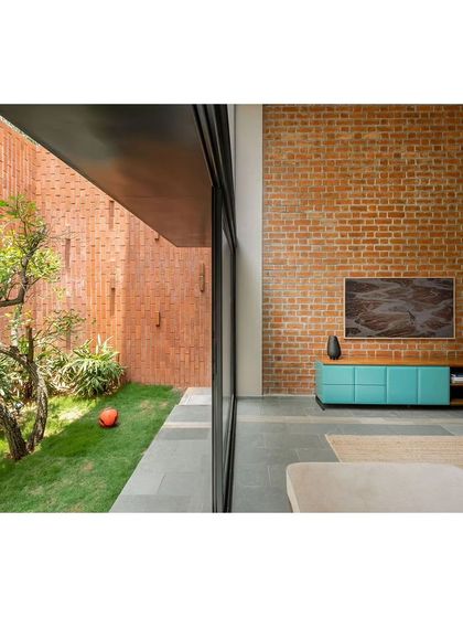 The living room opens up to a narrow but lush garden space. The high brick wall not only ensures privacy from neighbors but also becomes a beautiful, textured backdrop that enhances the feeling of a secluded oasis.