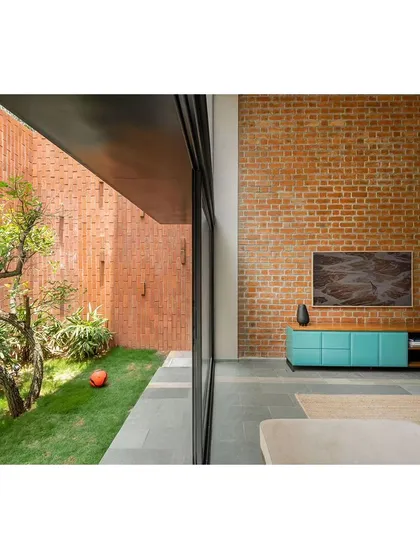 The living room opens up to a narrow but lush garden space. The high brick wall not only ensures privacy from neighbors but also becomes a beautiful, textured backdrop that enhances the feeling of a secluded oasis.