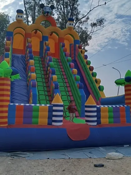 The 3-lane Mickey slide is fully inflated and ready for fun. A child is standing at the bottom, giving you a good sense of its size.