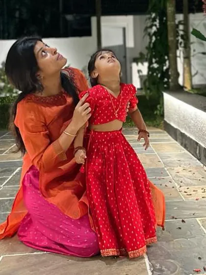 Kaanana looking up at the stars with her mother, looking super cute in the red bandhani-print lehenga set I designed for her.