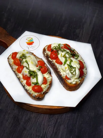 A slightly different angle of the caprese bruschetta, showing the fresh ingredients and glossy olive oil drizzle. The dark styling is great for creating a premium feel.
