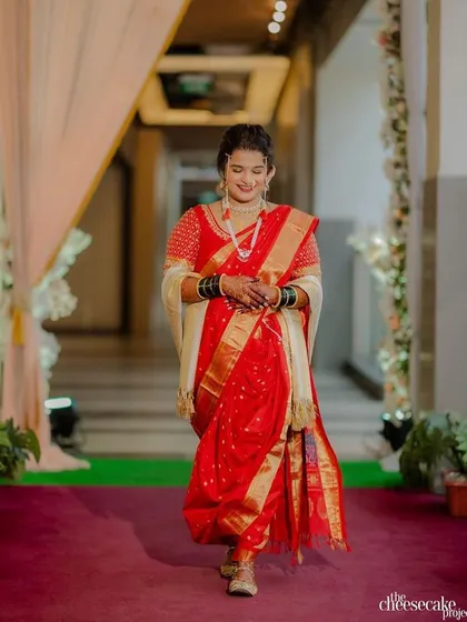 A stunning bride in a red Nauvari saree. The makeup is classic and bold, perfect for a traditional wedding ceremony.