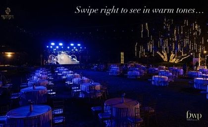 This image, with its "Swipe right to see in warm tones" text, shows the versatility of our lighting design. The same grand Sangeet setup could be transformed with a simple change in color.