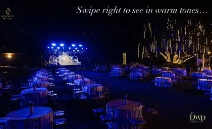 This image, with its "Swipe right to see in warm tones" text, shows the versatility of our lighting design. The same grand Sangeet setup could be transformed with a simple change in color.