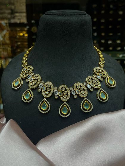 A beautiful Kundan necklace with oval motifs and mint-green drops. This is a very elegant piece that can be worn for parties and festive events.