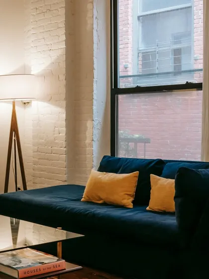A modern living room with a deep blue velvet sofa and a glass coffee table, perfect for a contemporary apartment. The design is clean, stylish, and functional.