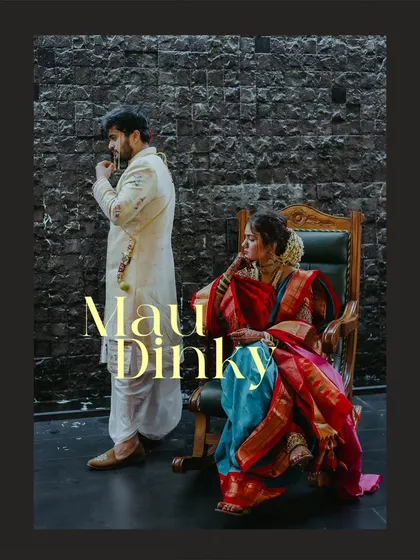 A regal and artistic portrait of the couple, with the bride seated in a rocking chair and the groom standing beside her.