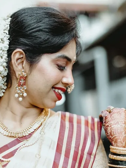 A candid moment showing the bride's joy. The drape of her saree remains immaculate, highlighting the detailed work on her blouse and her beautiful gajra hairstyle.