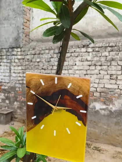 This rectangular clock combines natural wood with a vibrant yellow resin pour. It's a modern and cheerful piece of wall decor, seen here hanging from a tree branch in my studio garden.