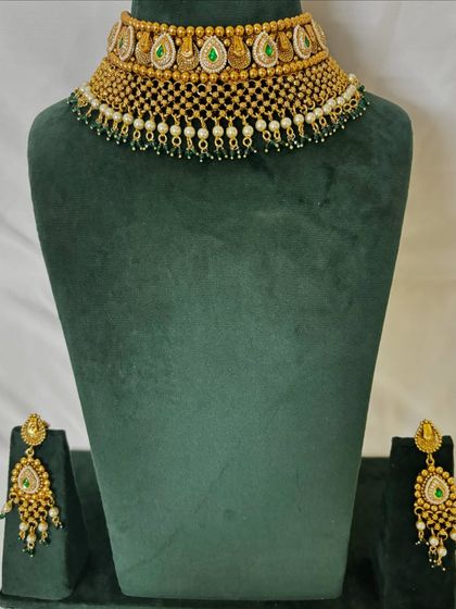 A gold-plated choker with temple coin motifs and green stones. This rental set is perfect for a South Indian bridal look.