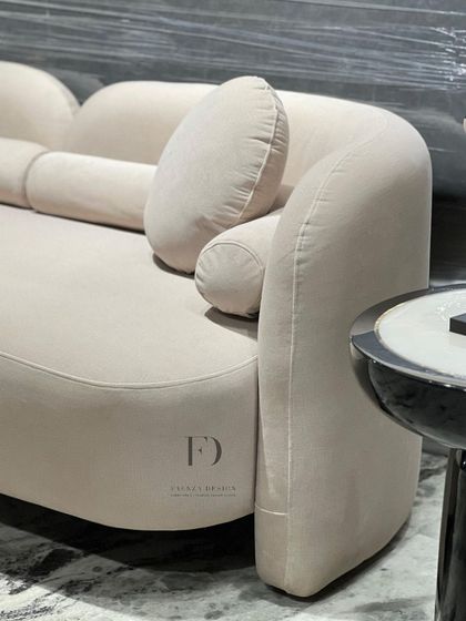 Different angles of a beautifully curved sofa in a neutral beige fabric. The soft, rounded forms and assortment of cylindrical and round cushions create an exceptionally comfortable and stylish seating experience.