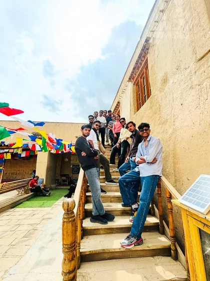 A group photo at a monastery, showcasing the unique architecture and the vibrant prayer flags that are a constant, beautiful presence throughout Spiti.