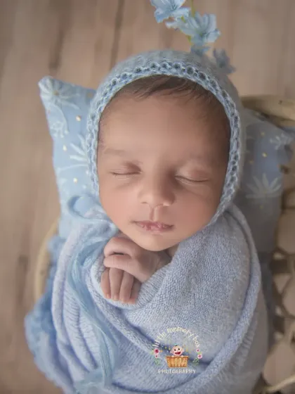 A slightly different angle of the hanging swing pose, showing the baby peacefully sleeping. The soft blue tones create a very calming and serene image.