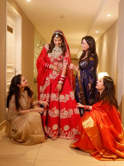 A heartwarming moment between the bride and her bridesmaids. They gather around her, helping with her lehenga, sharing smiles and creating a beautiful memory of friendship on her wedding day.