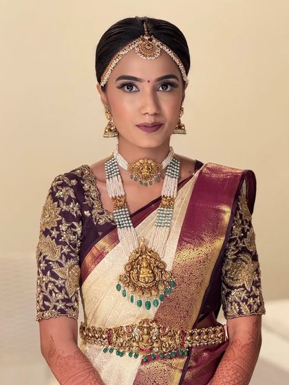 A classic portrait of a South Indian bride. The makeup is clean and timeless, with a focus on flawless skin and beautifully defined features to complement her temple jewelry.