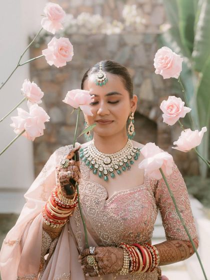 An artistic portrait of the bride surrounded by pink roses. Her serene expression and the creative framing make this a unique and beautiful bridal shot.