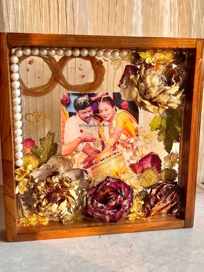 This 10-inch teakwood frame preserves a love story with wedding flowers and a sacred thread infinity symbol. It’s a beautiful way to represent a love that is meant to last forever.
