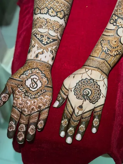 A close-up of the engagement mehendi, showing the couple's initial monogram and a delicate jhumka (earring) design.
