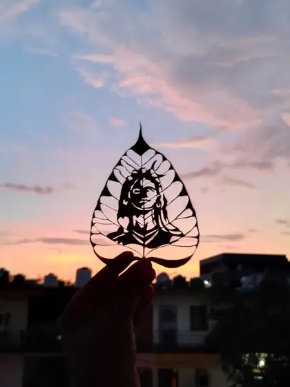 Here is one of my favorite leaf carvings, an image of Adi Yogi. I held it up to the sunset to show how the light passes through the delicate cuts, making the art glow. This is the magic of leaf art.