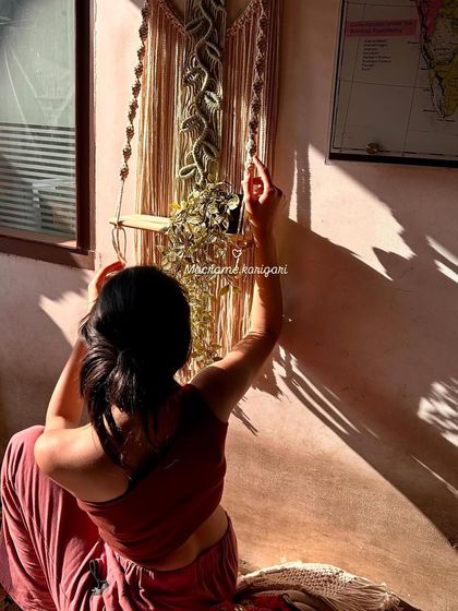 Adjusting a macramé wall shelf, a piece that combines beauty with utility. We started this journey to create things that not only look good but also serve a purpose in your home.